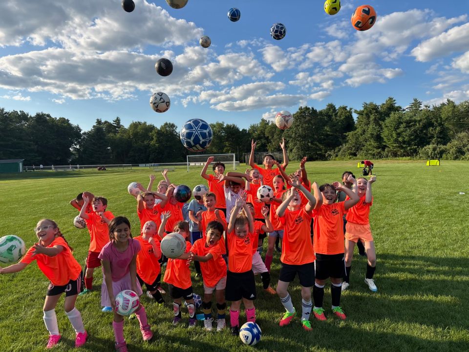 Campers celebrating with soccer balls in the air